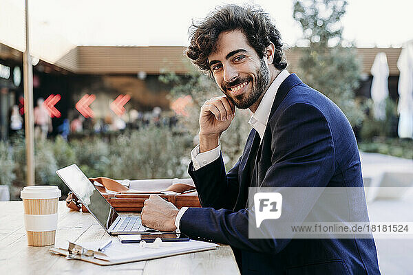 Handsome businessman with laptop at table working from cafe