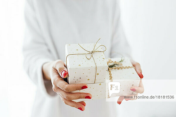 Woman giving Christmas presents against white background