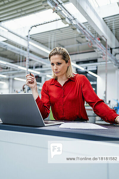 Konzentrierte Geschäftsfrau beobachtet Laptop in Fabrik