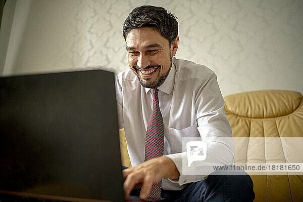 Happy businessman working on laptop at home