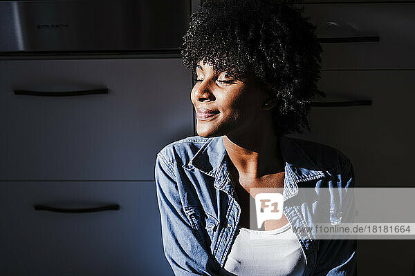 Smiling woman enjoying sunlight in kitchen at home