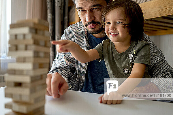 Curious boy playing block removal game with father at home