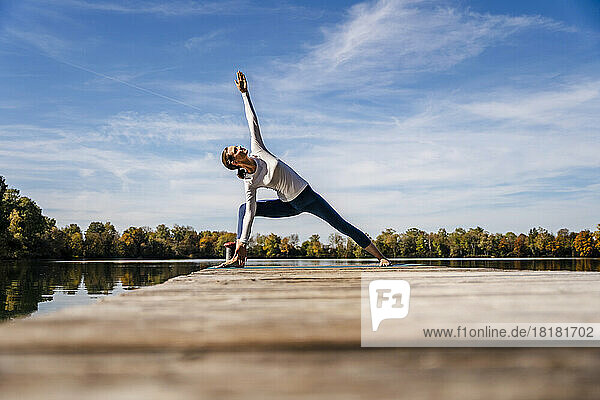 Woman exercising on jetty under sky
