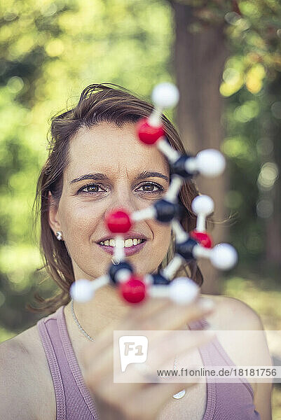 Smiling woman examining molecule model in park