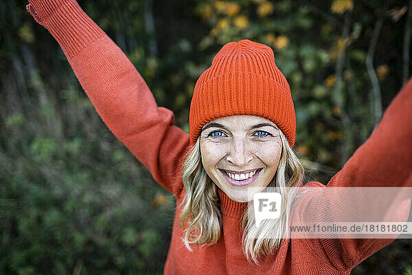 Lächelnde reife Frau mit orangefarbener Strickmütze am Wochenende