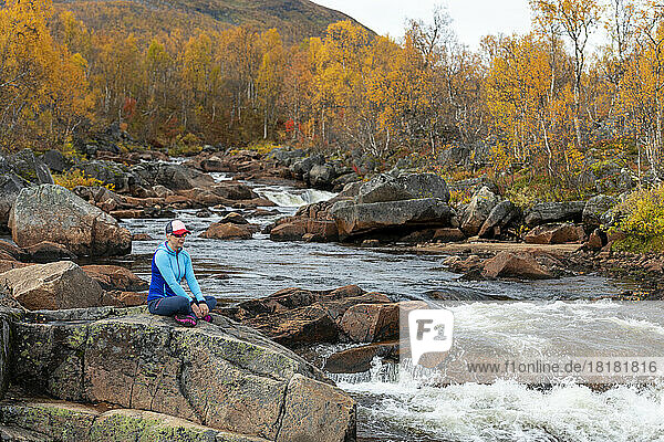 Woman sitting on rocks at riverbank