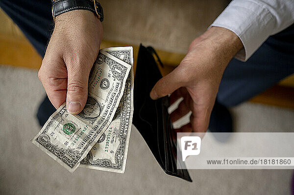 Man holding US dollar bills and wallet