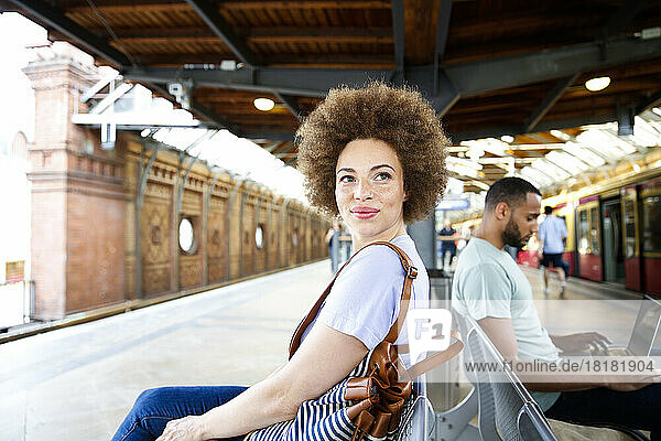 Young woman sitting on bench at train station