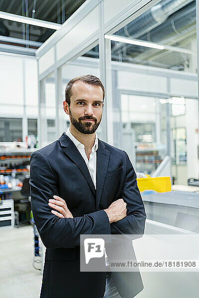 Businessman wearing blazer standing with arms crossed in industry