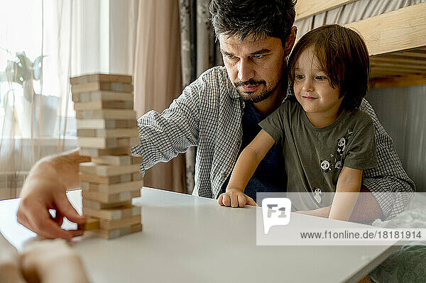 Father teaching son to play block removal game at home