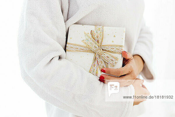 Woman holding Christmas gift against white background