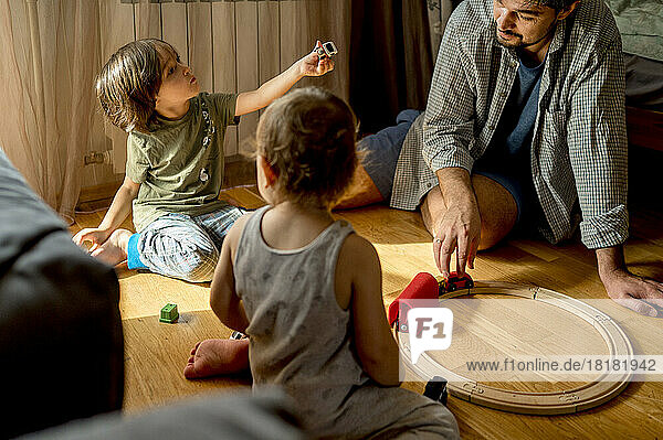 Father and sons spending leisure time playing with toys at home
