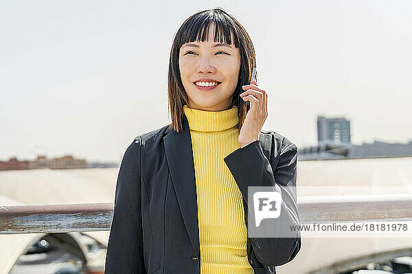 Happy young woman talking through smart phone on sunny day