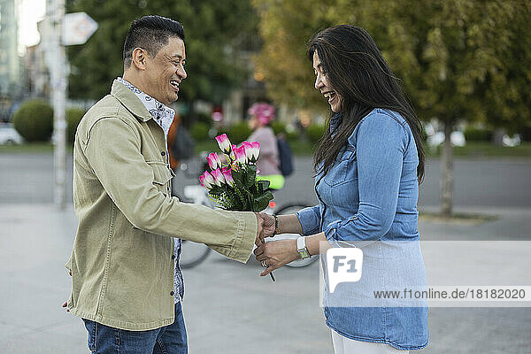 Glücklicher Mann  der Frau am Valentinstag Blumen schenkt