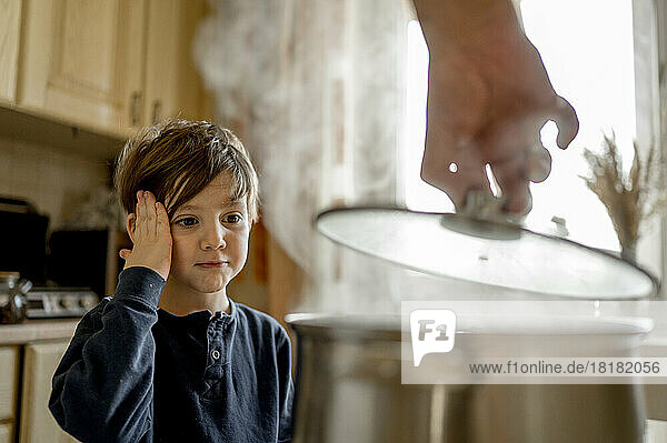 Boy looking at hot soup in kitchen