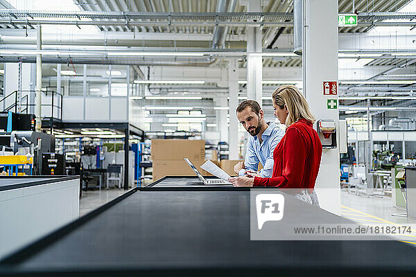 Business colleagues working on laptop at table in factory