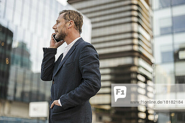 Businessman talking over smart phone in front of building