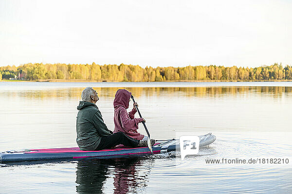 Älterer Mann und Enkelin paddeln im See