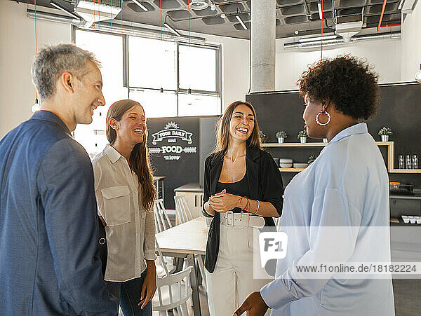 Happy businessman talking with businesswomen in cafeteria