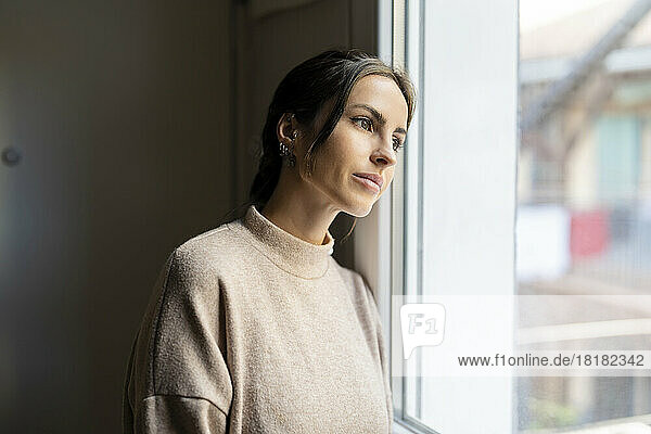 Thoughtful woman looking out of window at home