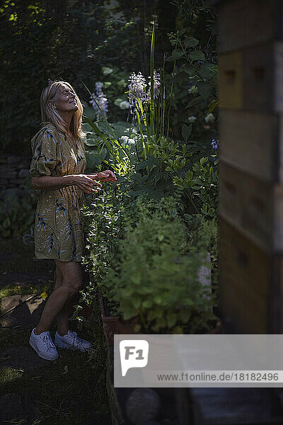 Mature woman with eyes closed standing by plants in garden