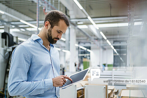 Businessman touching screen of tablet PC at factory