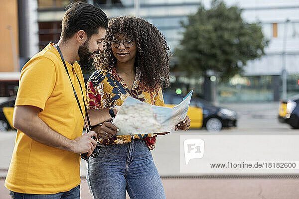 Young couple on vacations discussing over map at footpath