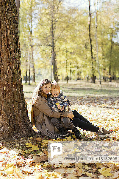 Cute boy sitting on mother's lap in park