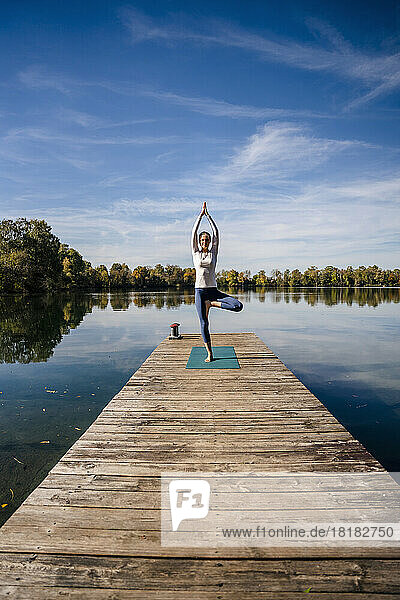 Woman practicing yoga on sunny day under sky