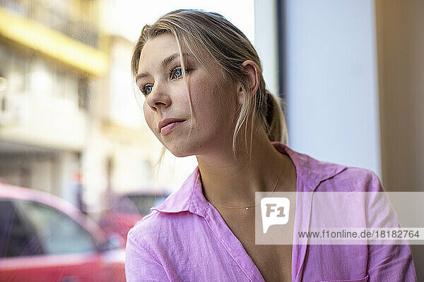 Contemplative woman leaning on glass in cafe