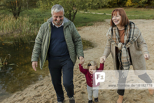 Grandparents walking on sand with granddaughter
