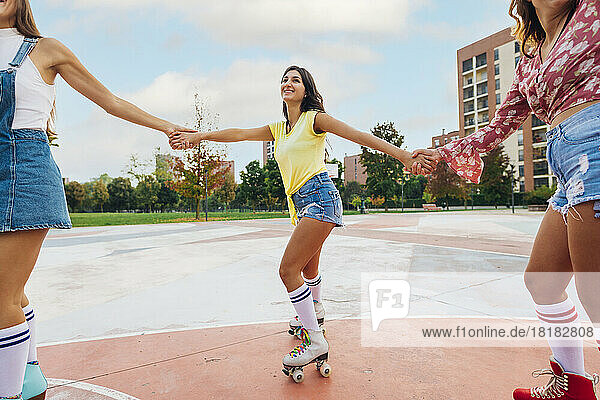 Smiling woman skating with friends at sports court