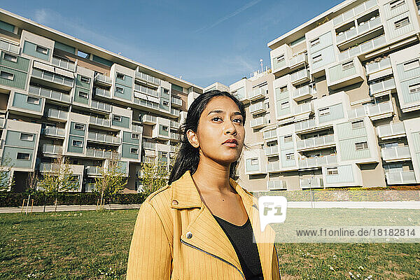 Junge Frau vor Wohngebäuden an einem sonnigen Tag