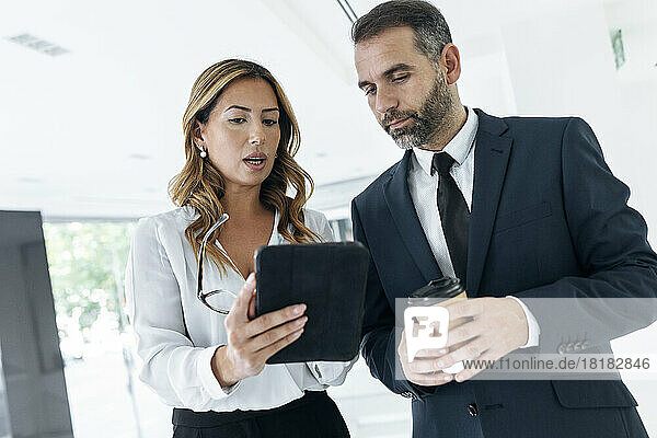 Businesswoman sharing tablet PC with colleague in office