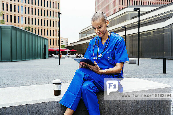 Mature nurse using tablet PC sitting on bench