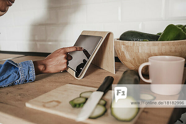 Hands of woman using tablet PC at kitchen counter