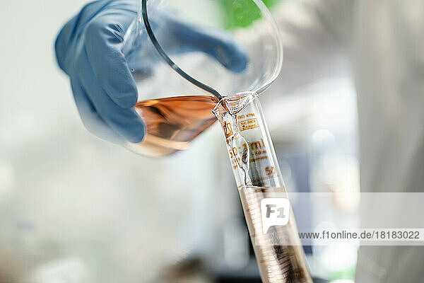 Hand eines Wissenschaftlers  der im Labor Chemikalien in ein Reagenzglas gießt