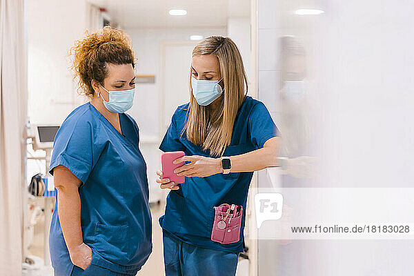 Nurses discussing and using smart phone at hospital