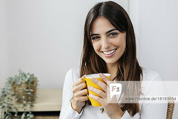 Happy woman holding coffee cup at home