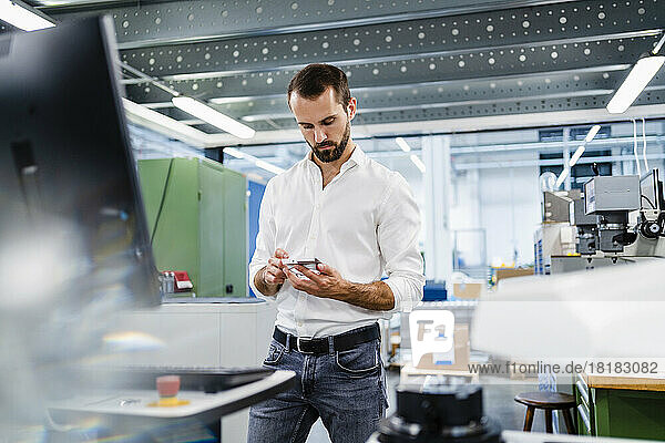 Businessman looking at machine part in factory