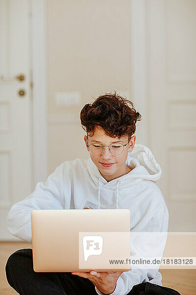 Lächelnder Junge  der zu Hause einen Laptop benutzt