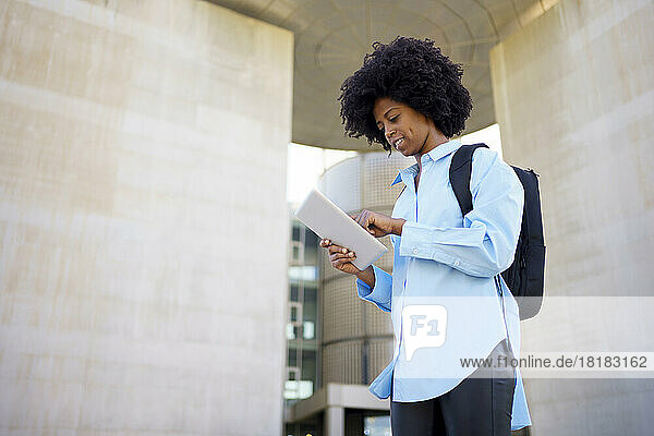 Businesswoman using tablet PC standing amidst wall