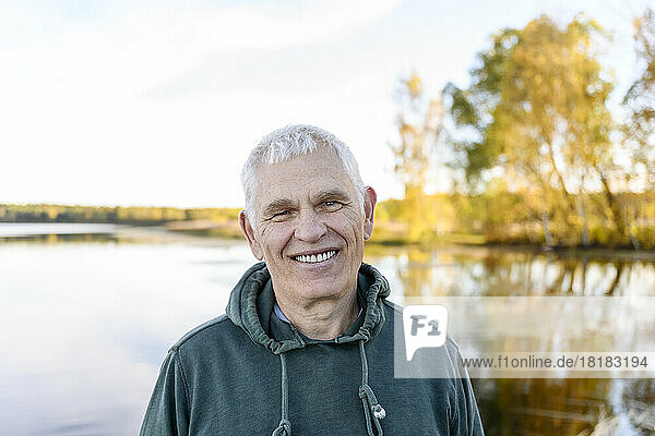 Smiling senior man in front of lake