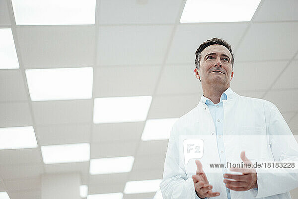 Smiling man in lab coat gesturing