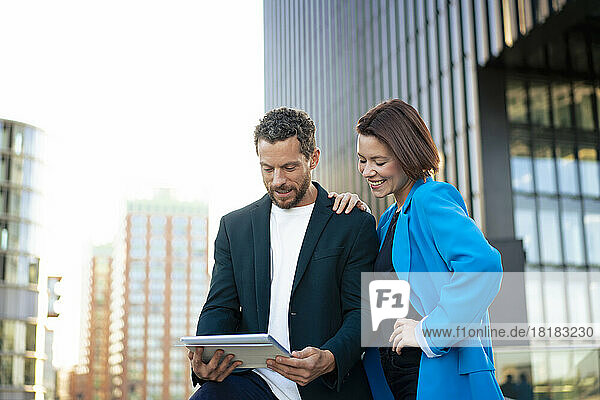 Smiling business colleagues sharing tablet PC with each other
