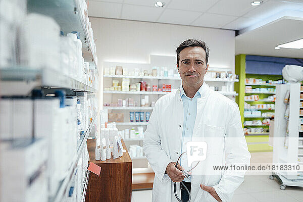 Man in lab coat holding stethoscope in pharmacy