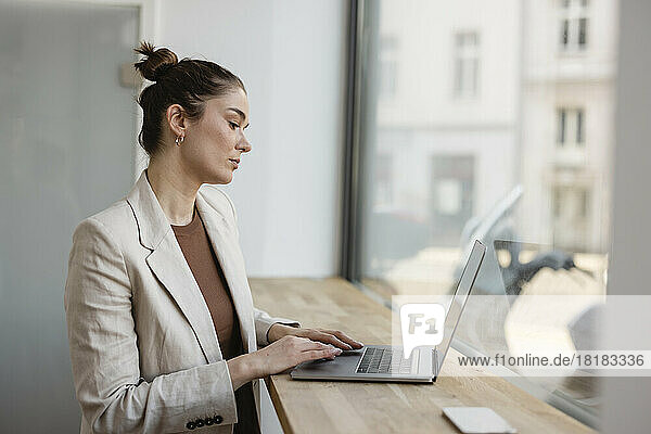 Businesswoman using laptop on table in office