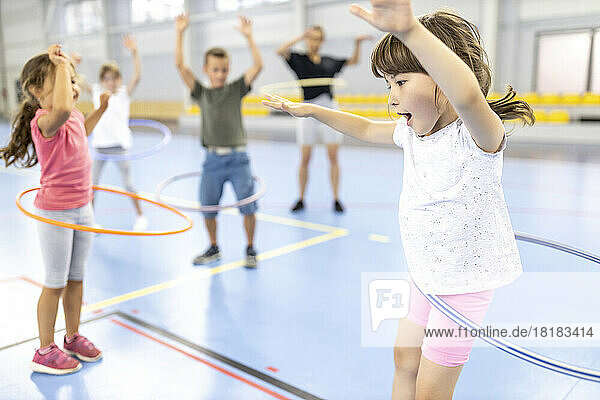 Students practicing hula hoops with each other at school sports court