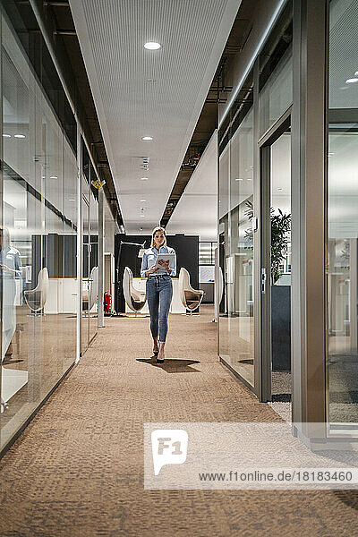 Businesswoman with tablet PC walking in office corridor