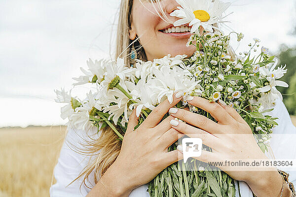 Happy woman with bunch of white daises flower at field
